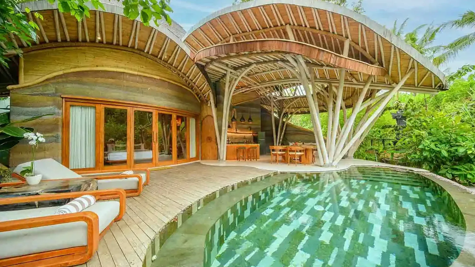 Curved bamboo pavilion beside a green-tiled villa pool in Tabanan, Bali