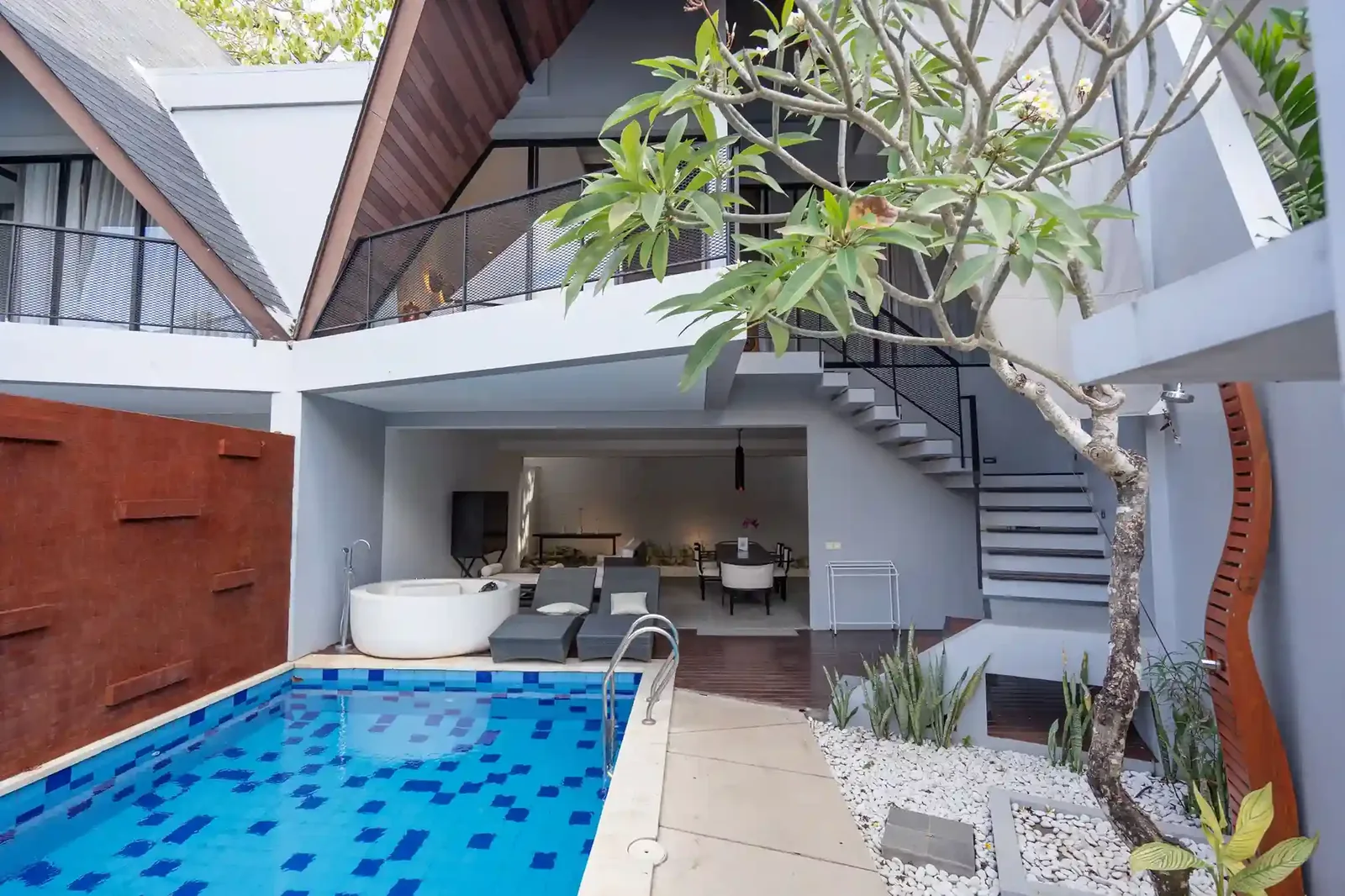 Villa courtyard pool with a frangipani tree and open-plan living area behind