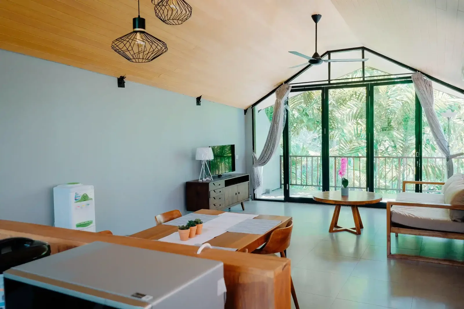 Villa living room with vaulted timber ceiling and full-height glazing onto the garden