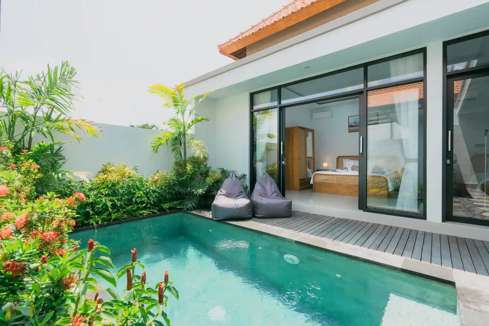 Private villa pool edged with tropical planting, opening onto a bedroom pavilion